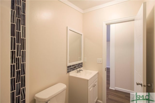 bathroom featuring vanity, hardwood / wood-style flooring, ornamental molding, and toilet