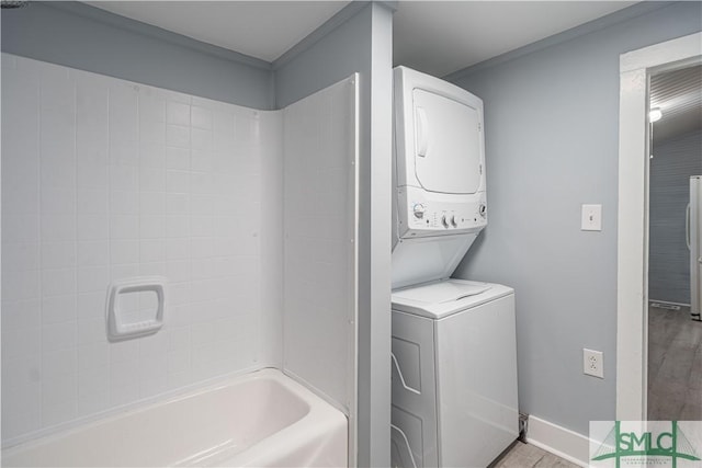 clothes washing area featuring light tile patterned floors and stacked washing maching and dryer