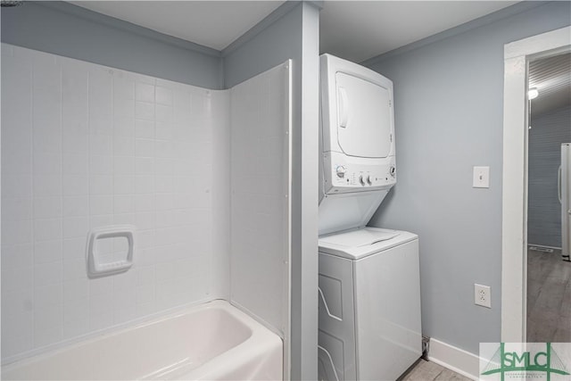 washroom featuring baseboards, stacked washer / drying machine, and laundry area