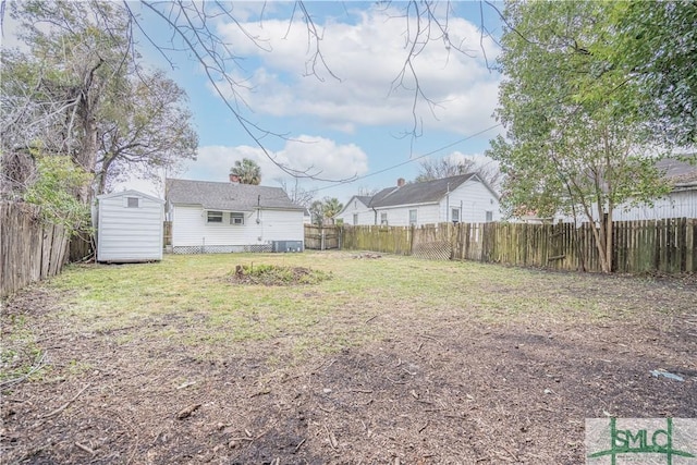 view of yard featuring a fenced backyard, a storage unit, and an outbuilding