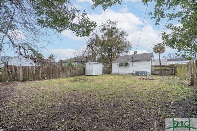 view of yard with central air condition unit, a fenced backyard, a shed, and an outbuilding