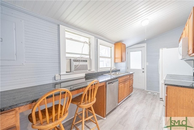 kitchen featuring stainless steel dishwasher, lofted ceiling, dark countertops, a sink, and light wood finished floors