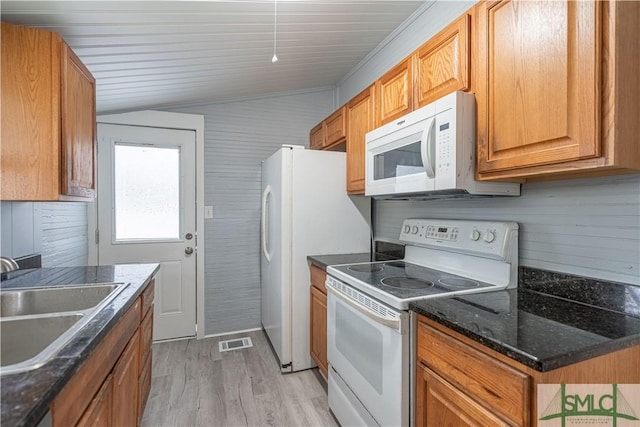 kitchen featuring sink, dark stone counters, white appliances, and light hardwood / wood-style floors