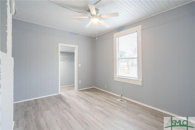 unfurnished bedroom with visible vents, ceiling fan, wood finished floors, and a walk in closet