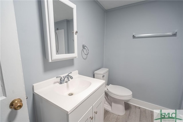 bathroom featuring toilet, baseboards, wood finished floors, and vanity
