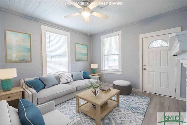 living area with baseboards, a ceiling fan, wood finished floors, and wood walls