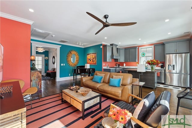 living room featuring dark hardwood / wood-style flooring, sink, crown molding, and ceiling fan