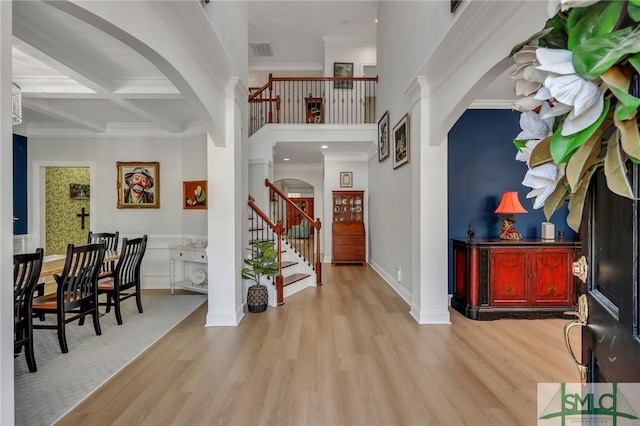 entrance foyer featuring beamed ceiling, crown molding, coffered ceiling, and light hardwood / wood-style floors