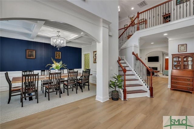 dining space with crown molding, an inviting chandelier, coffered ceiling, beamed ceiling, and light wood-type flooring