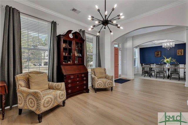 sitting room with an inviting chandelier, ornamental molding, and light wood-type flooring