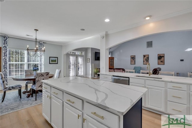 kitchen featuring white cabinetry, sink, stainless steel dishwasher, and a center island