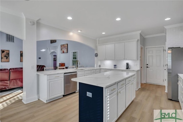 kitchen with stainless steel appliances, kitchen peninsula, sink, and white cabinets