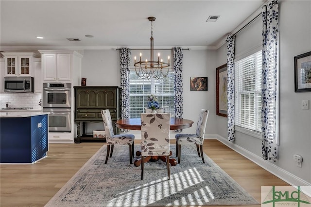 dining space with crown molding, a chandelier, and light wood-type flooring