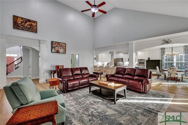 living room with ceiling fan with notable chandelier, hardwood / wood-style flooring, high vaulted ceiling, and a wealth of natural light