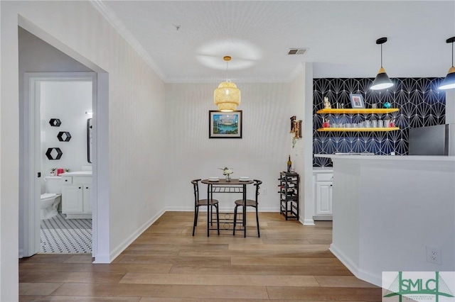 bar with wood-type flooring, crown molding, and decorative light fixtures