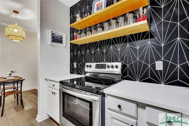 kitchen featuring hanging light fixtures, wood-type flooring, white cabinets, and stainless steel electric range