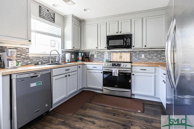 kitchen featuring sink, butcher block counters, stainless steel appliances, dark hardwood / wood-style floors, and decorative backsplash