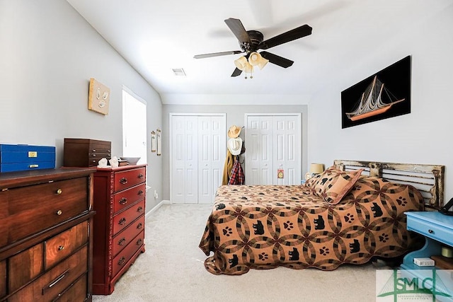 bedroom with light carpet, multiple closets, and ceiling fan