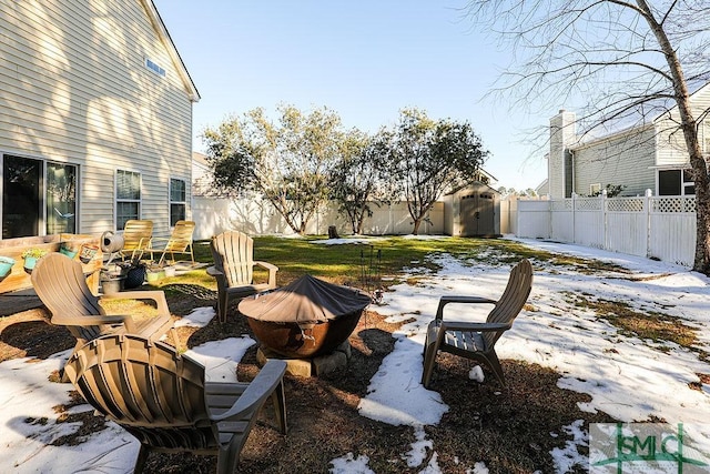 yard layered in snow with a storage unit and an outdoor fire pit