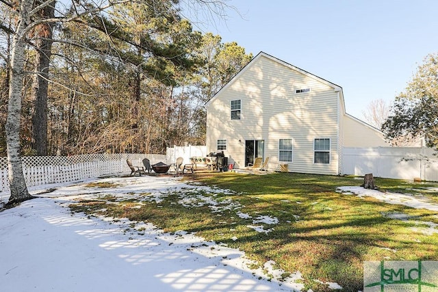 snow covered property featuring an outdoor fire pit and a lawn