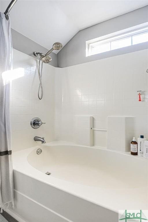 bathroom featuring plenty of natural light, shower / bathtub combination with curtain, and vaulted ceiling