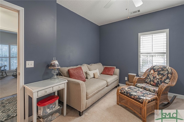 carpeted living room featuring ceiling fan and a textured ceiling