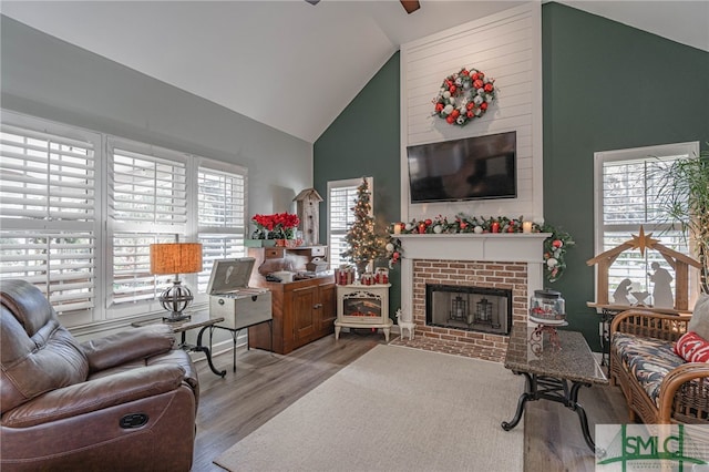 living room with a fireplace, high vaulted ceiling, and light wood-type flooring