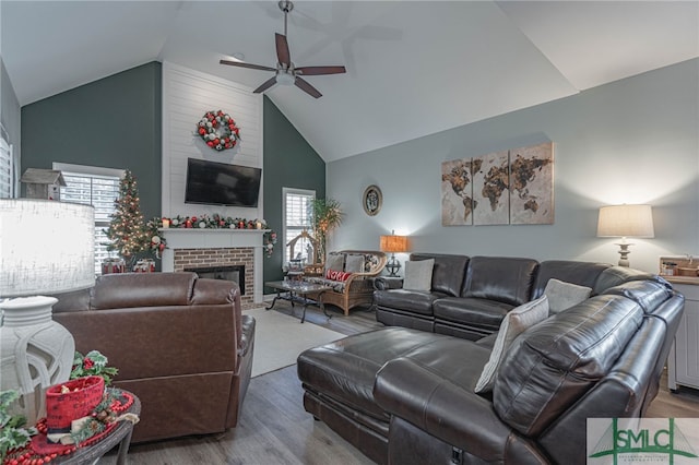 living room with wood-type flooring, high vaulted ceiling, a brick fireplace, and a wealth of natural light