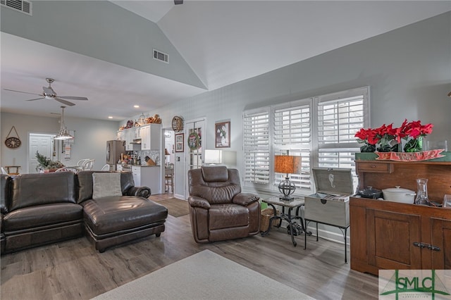 living room with ceiling fan, lofted ceiling, and light wood-type flooring