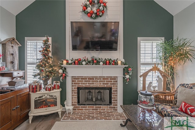 living room featuring wood-type flooring, high vaulted ceiling, and a fireplace