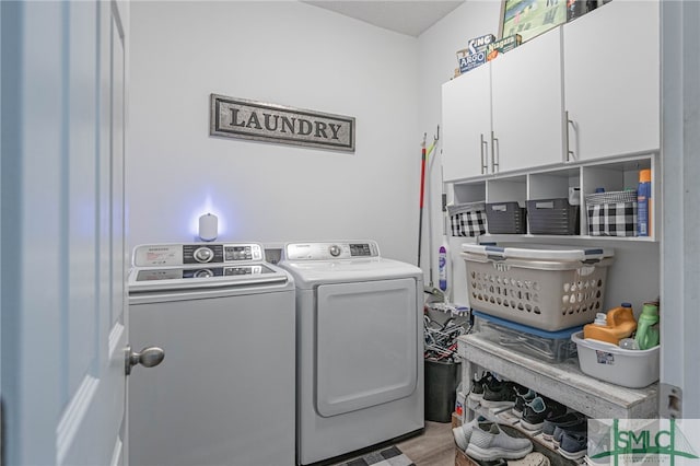 clothes washing area featuring cabinets, washing machine and clothes dryer, and light hardwood / wood-style floors