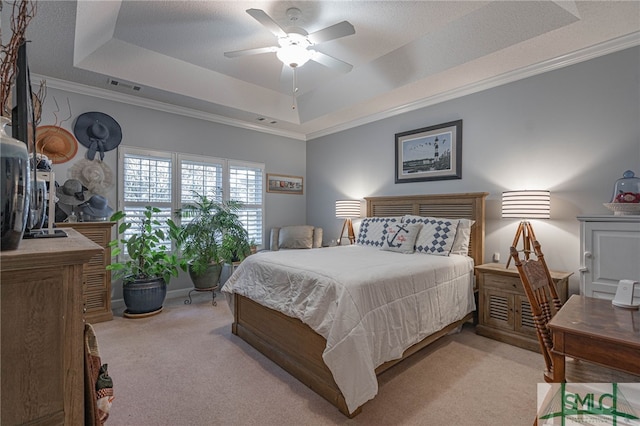 bedroom featuring ornamental molding, light colored carpet, a raised ceiling, and ceiling fan