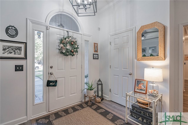 entrance foyer with an inviting chandelier, crown molding, and wood-type flooring