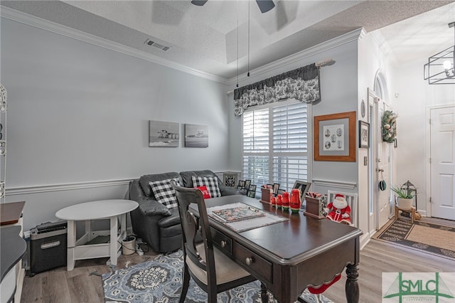 dining space with hardwood / wood-style floors, a tray ceiling, ornamental molding, and a textured ceiling