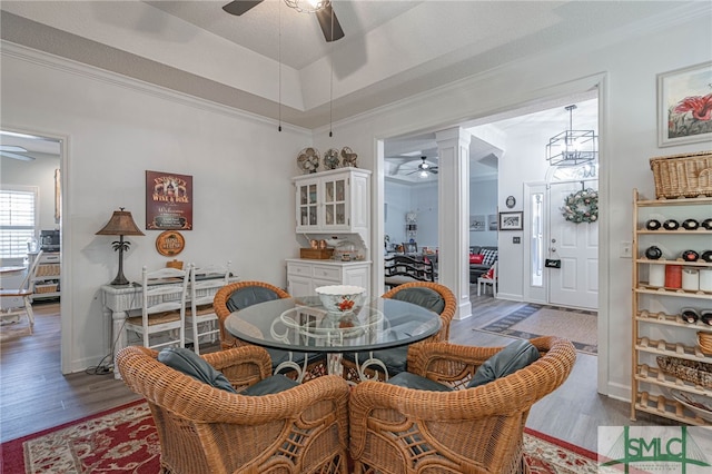 dining space with hardwood / wood-style flooring, ornamental molding, and a raised ceiling