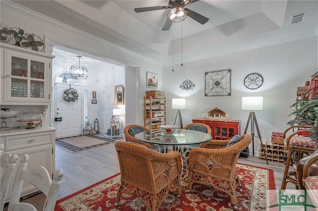 dining area featuring crown molding, a tray ceiling, and light wood-type flooring