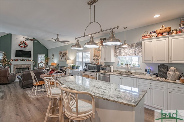 kitchen featuring white cabinetry, hanging light fixtures, vaulted ceiling, and sink