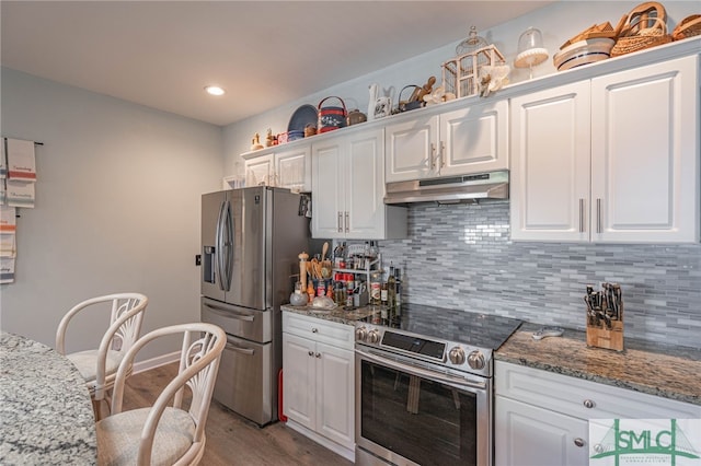 kitchen featuring light hardwood / wood-style flooring, stone counters, appliances with stainless steel finishes, white cabinets, and decorative backsplash