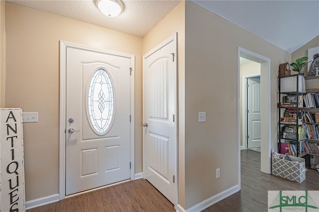 entrance foyer featuring lofted ceiling, hardwood / wood-style floors, and a textured ceiling