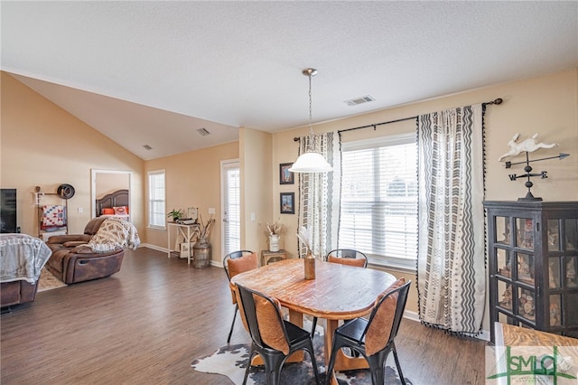 dining space featuring dark wood-type flooring, plenty of natural light, and vaulted ceiling