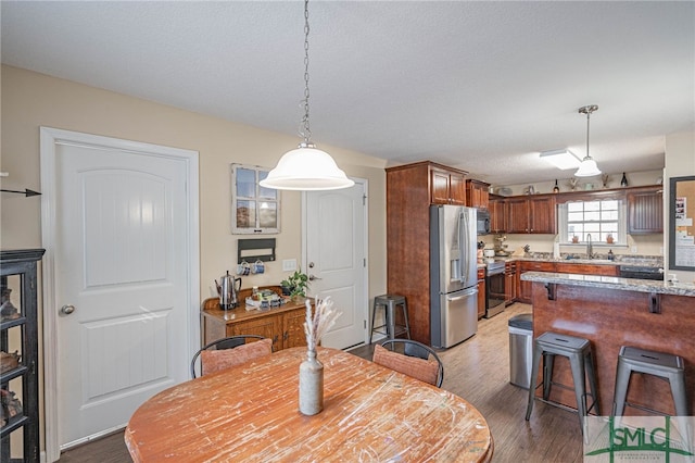 dining area with sink, hardwood / wood-style flooring, and a textured ceiling