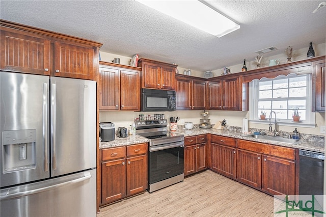 kitchen with light stone countertops, sink, a textured ceiling, and black appliances