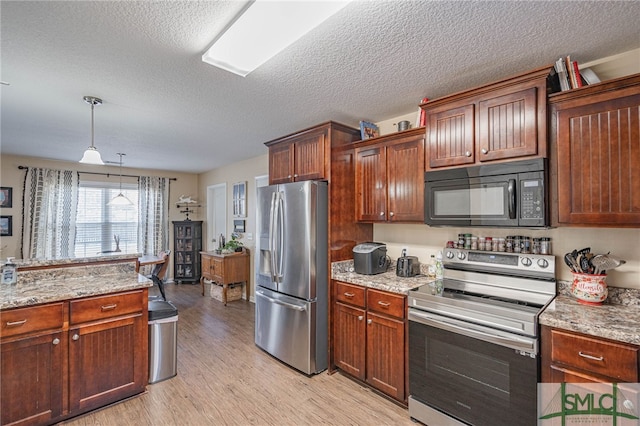 kitchen with pendant lighting, light stone counters, light hardwood / wood-style floors, and appliances with stainless steel finishes