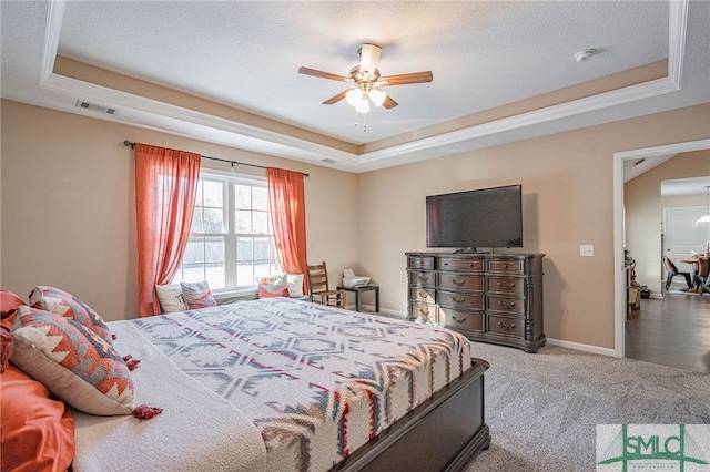 carpeted bedroom featuring a textured ceiling, ceiling fan, and a tray ceiling