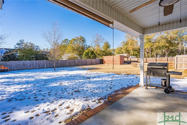 yard layered in snow with a patio and ceiling fan