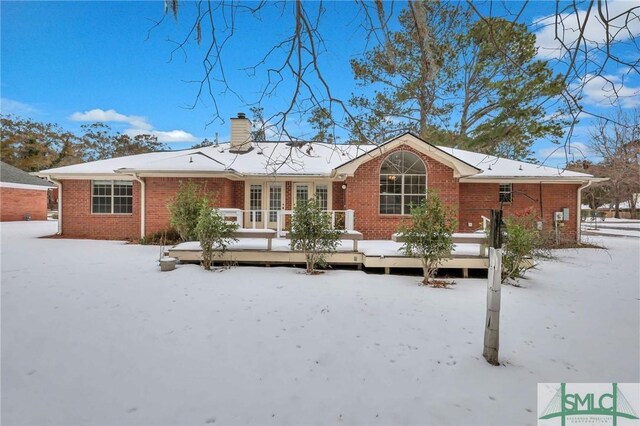 snow covered rear of property with a deck