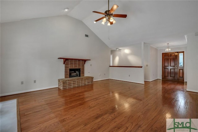 unfurnished living room with lofted ceiling, a brick fireplace, dark wood-type flooring, and ceiling fan