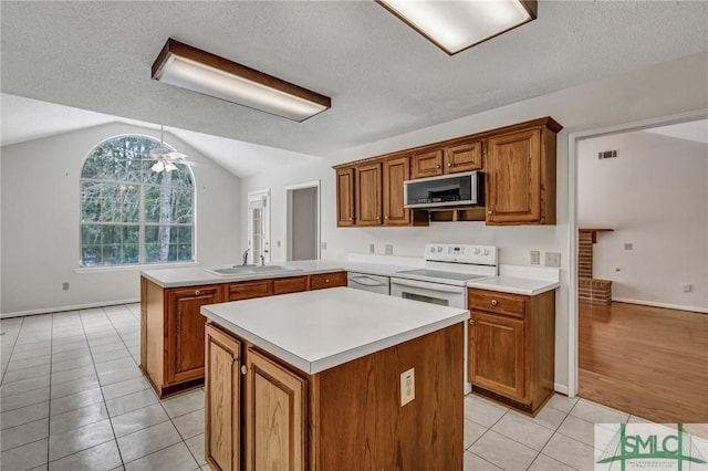 kitchen with white electric range oven, sink, light tile patterned floors, kitchen peninsula, and a kitchen island