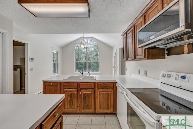 kitchen with light tile patterned flooring, washer / dryer, sink, vaulted ceiling, and white appliances