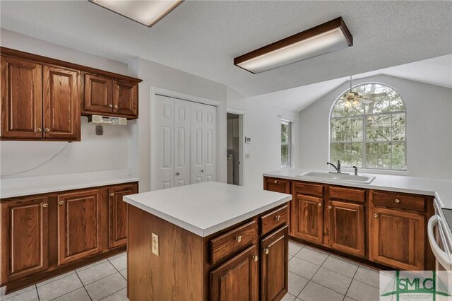 kitchen featuring vaulted ceiling, a kitchen island, sink, light tile patterned floors, and ceiling fan